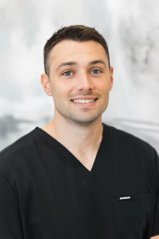 a man wearing a black scrub top with the name damian on it
