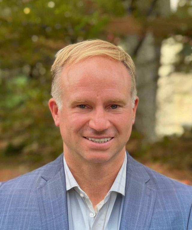a man in a suit and white shirt is smiling for the camera .