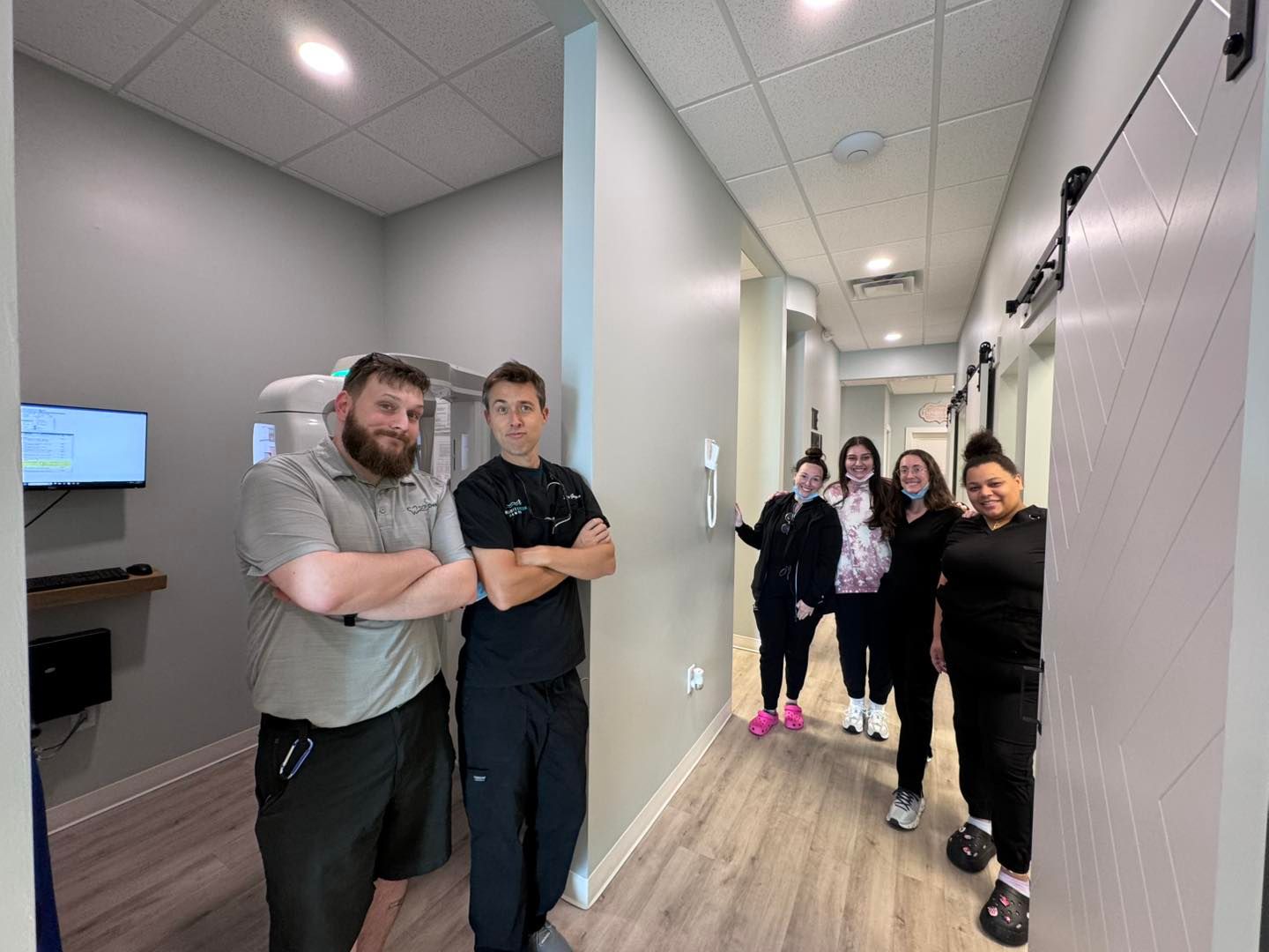 a group of people are standing in a hallway in a dental office .