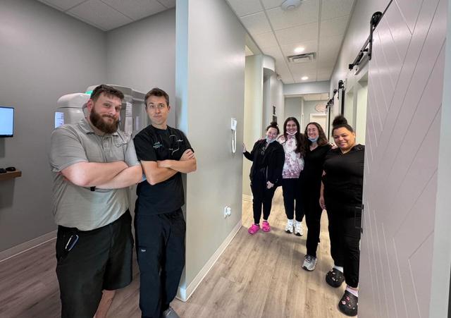 a group of people are standing in a hallway in a dental office .