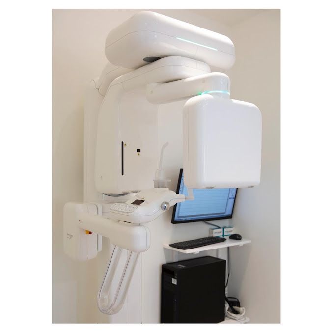 a dental x-ray machine is sitting in a room next to a computer .