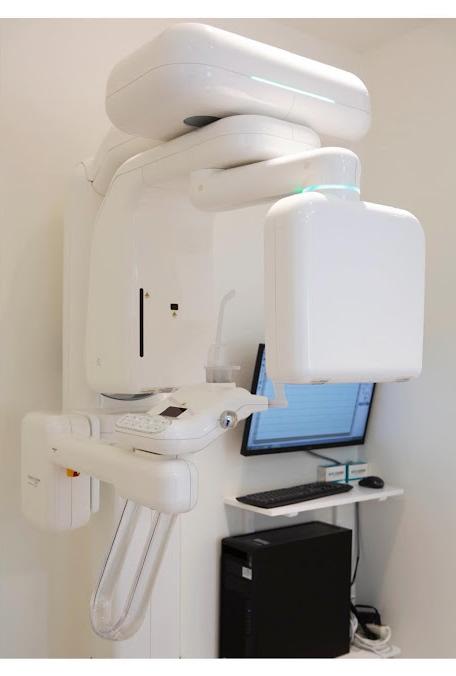 a dental x-ray machine is sitting in a room next to a computer .