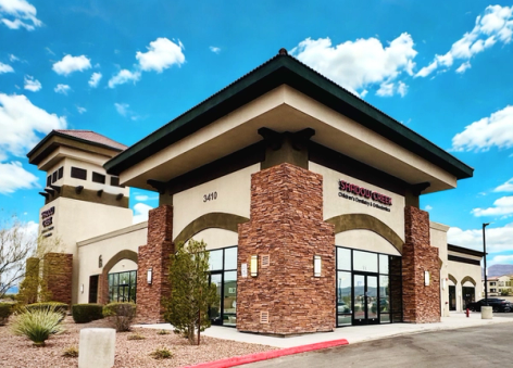 Exterior of Shadow Creek Children's Dentistry & Orthodontics, a modern building with stucco walls and stone accents, under a bright blue sky.