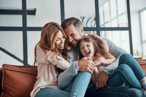 a family is sitting on a couch and laughing together