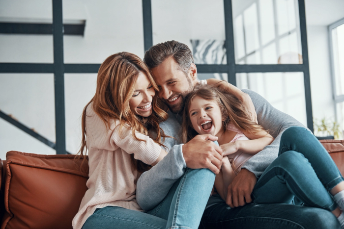 a family is sitting on a couch and laughing together