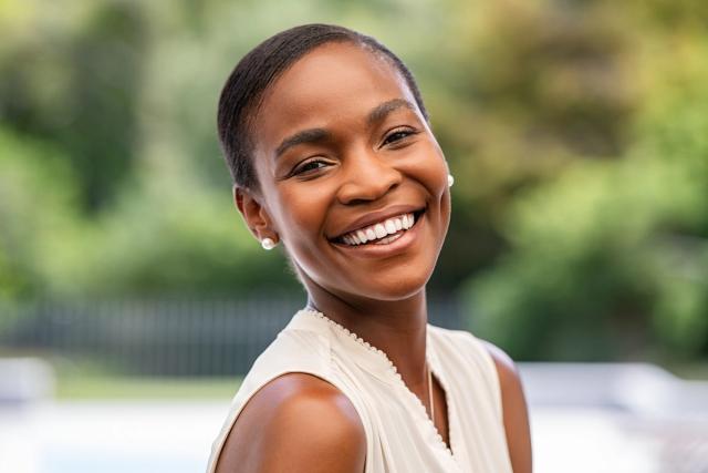 a woman in a white shirt is smiling and looking at the camera .