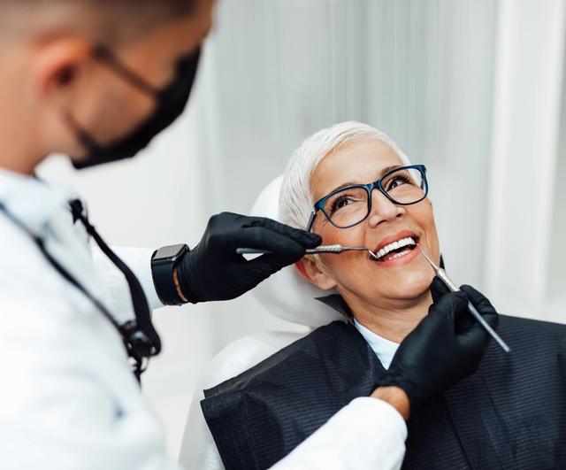 a woman is sitting in a dental chair while a dentist examines her teeth .