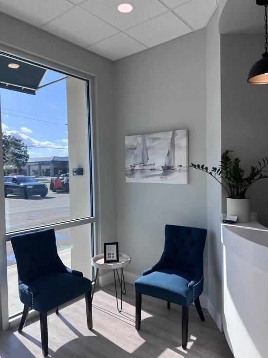 a waiting room with two chairs and a painting of sailboats on the wall .