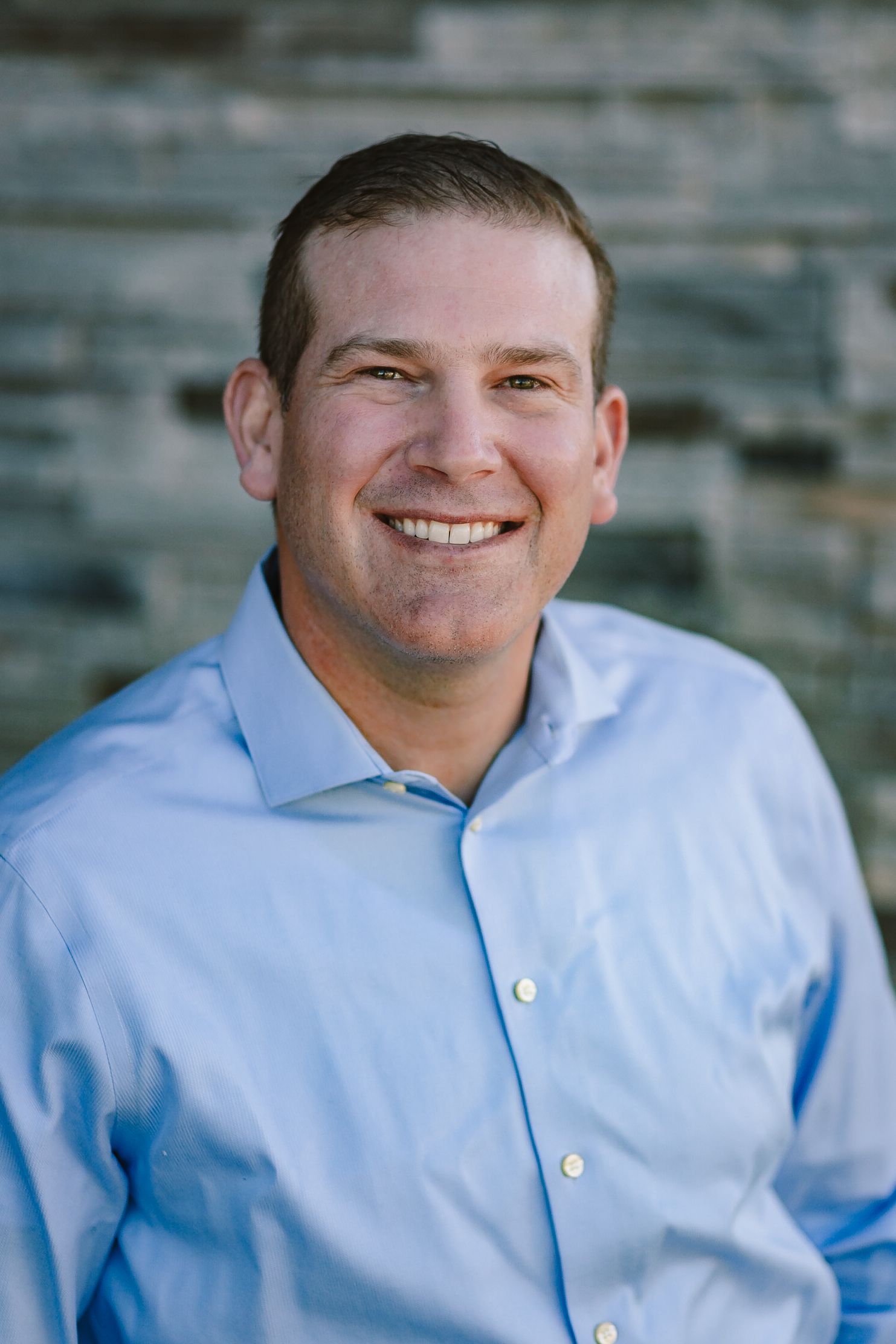 a man in a blue shirt is smiling for the camera