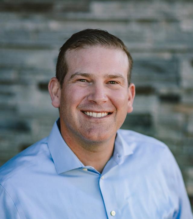 a man in a blue shirt is smiling for the camera