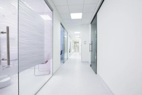 a long hallway in a hospital with glass doors and white walls .