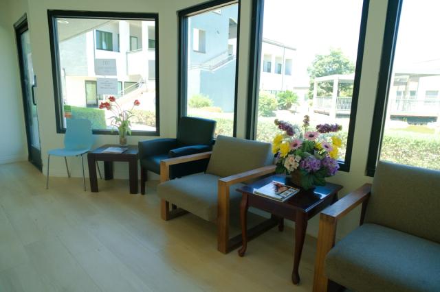 a waiting room with chairs , tables and a vase of flowers .