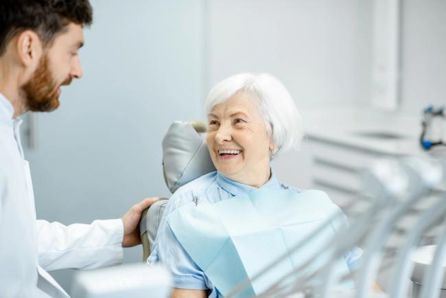 an elderly woman is smiling while sitting in a dental chair .