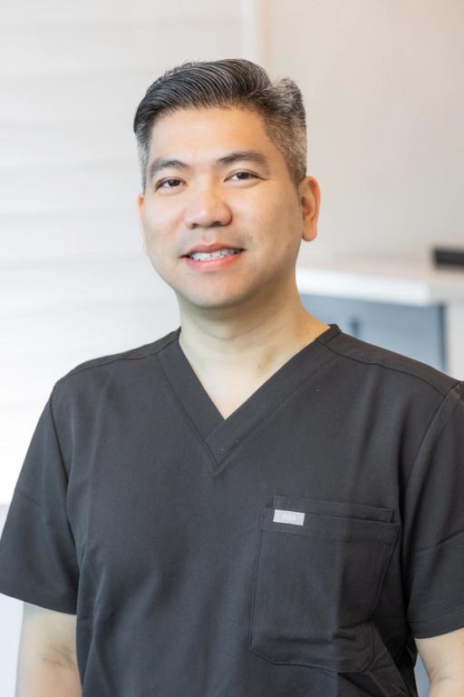 a man wearing a black scrub top with a white label on the pocket