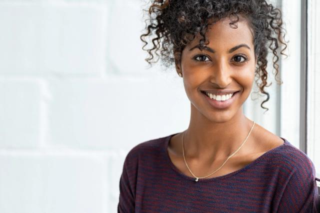 a woman with curly hair is smiling and looking at the camera .