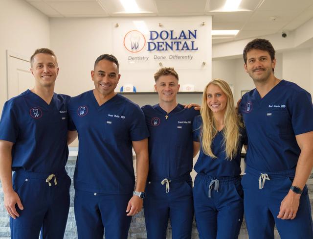 a group of dentists are posing for a picture in front of a dental office .