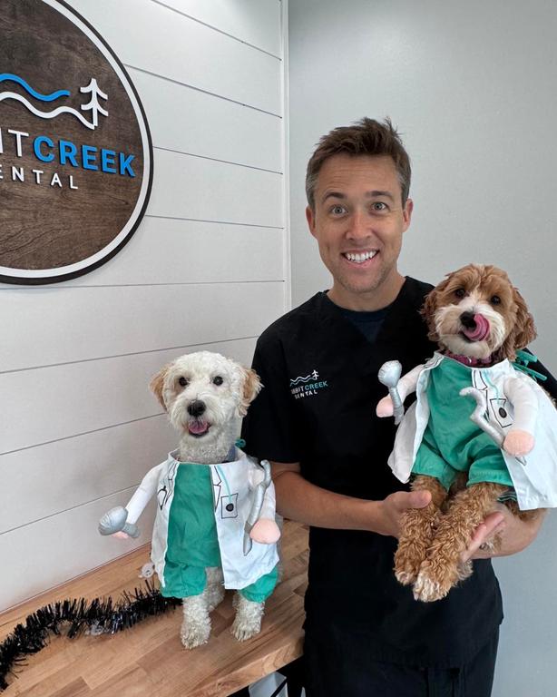 a man is holding two small dogs dressed as doctors
