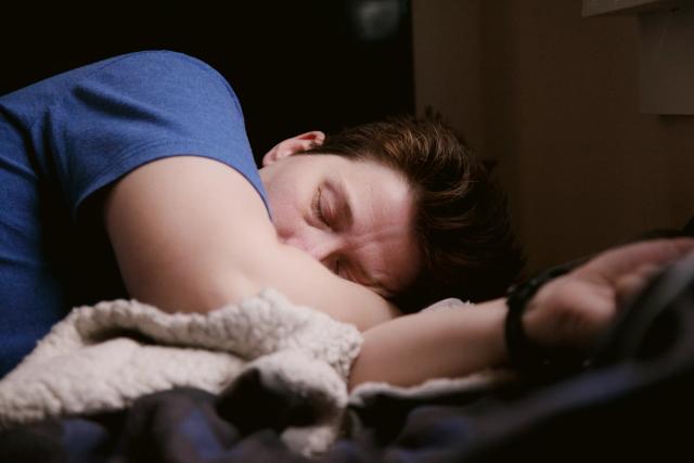 a man is sleeping on a bed with his head on his arm .