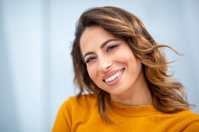 a woman in a yellow shirt is smiling for the camera .