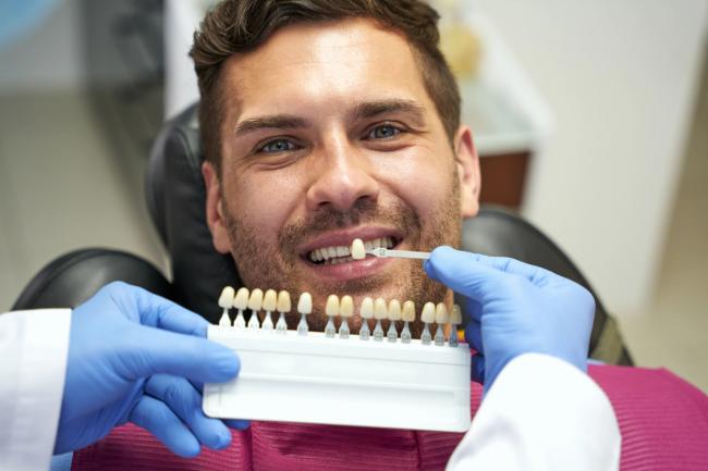 a man is sitting in a dental chair while a dentist examines his teeth .