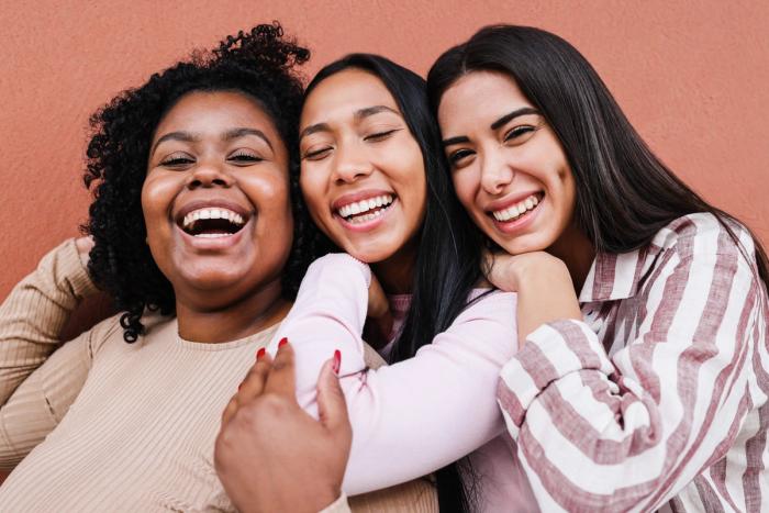 three women are laughing together and hugging each other .