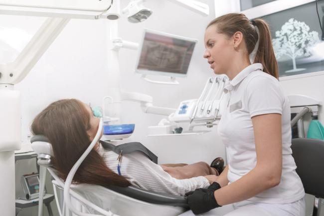 Female dentist talking to a female patient in a dental chair.