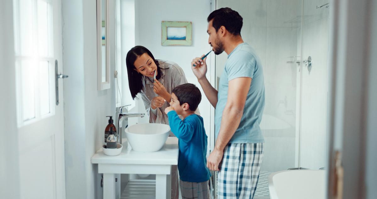 a family is brushing their teeth together in the bathroom .