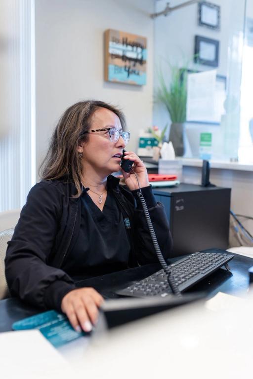 a woman is sitting at a desk talking on a phone