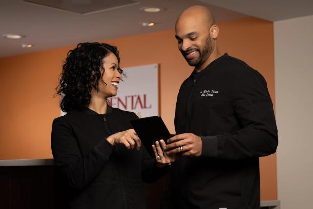 a man and a woman are standing next to each other in a dental office .