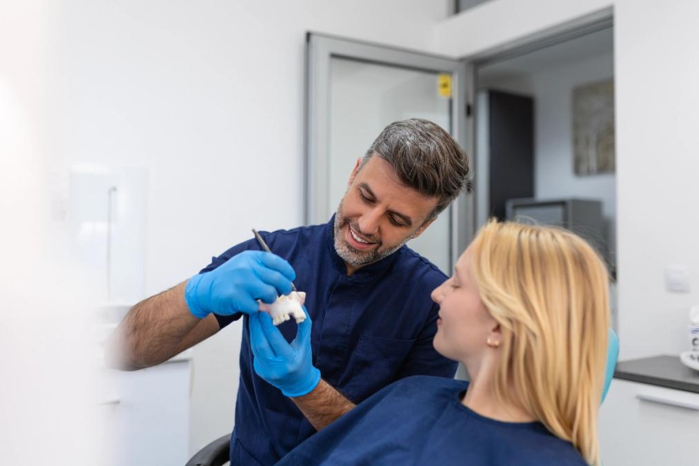a dentist is examining a patient 's teeth in a dental office .