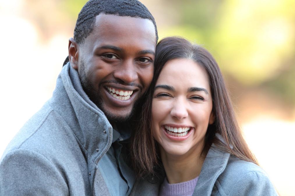 A smiling man and a laughing woman in winter coats.