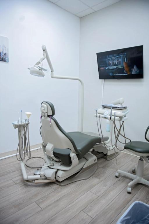 un consultorio dental con una silla dental y un monitor.
