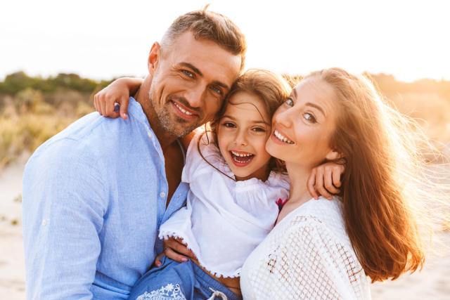 a happy family is posing for a picture on the beach .