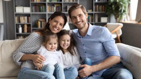 a family is sitting on a couch in a living room .
