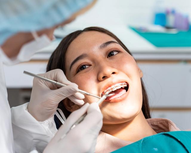a woman with braces is getting her teeth examined by a dentist .