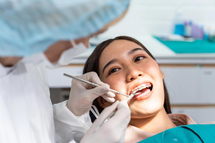 a woman with braces is getting her teeth examined by a dentist .