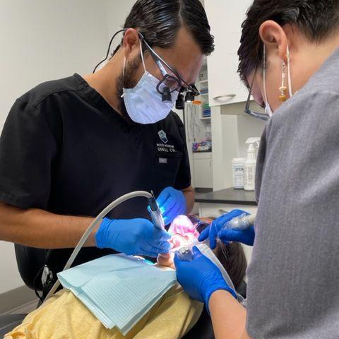 a dentist is working on a child 's teeth with a drill