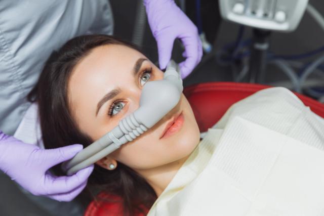 a woman is laying in a dental chair with an oxygen mask on her face .