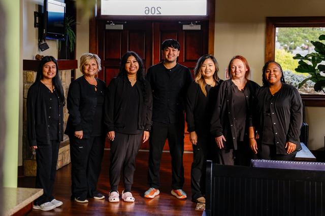 a group of dental assistants are posing for a picture in a dental office .