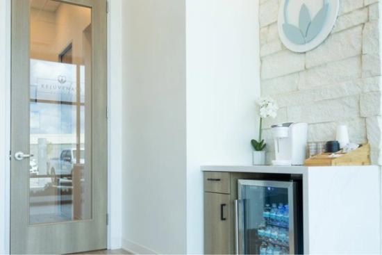 a room with a refrigerator filled with water bottles and a coffee maker .