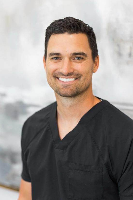 a man in a black scrub top is smiling for the camera .