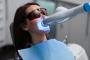 a woman is getting her teeth whitened in a dental office .