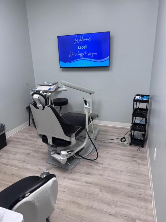a dental office with a dental chair and a tv that says welcome lacell