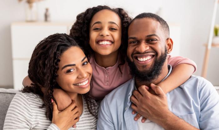 a family is posing for a picture while sitting on a couch .