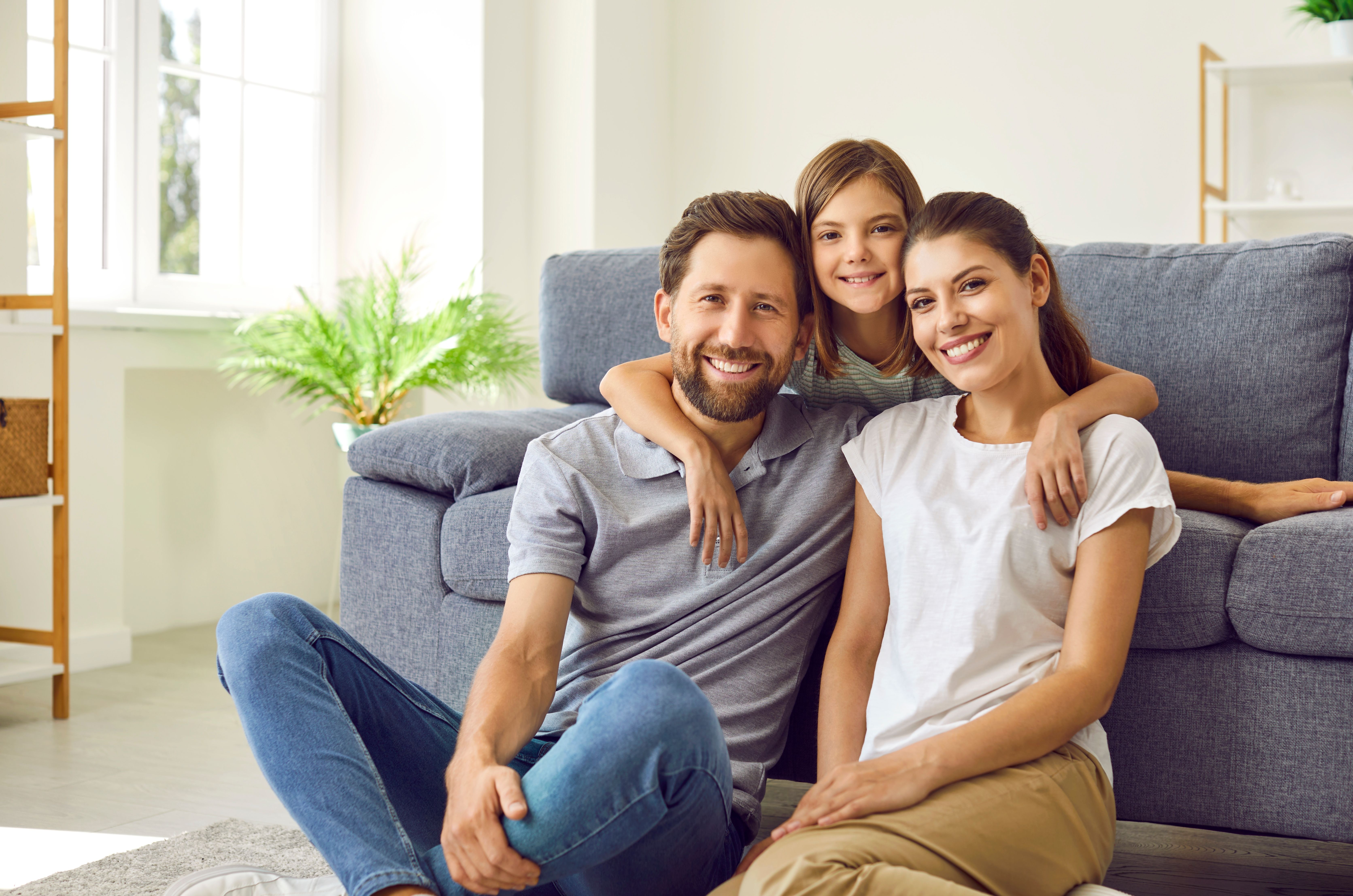 a family is posing for a picture while sitting on the floor in front of a couch .
