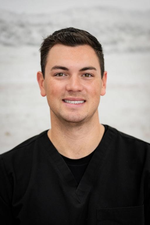 a man in a black scrub top is smiling for the camera .