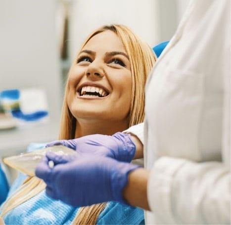a woman is smiling while sitting in a dental chair .