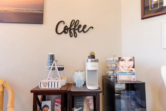 there is a coffee station in the waiting room of a dental office .