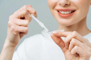 a woman is applying teeth whitening gel to a clear tray .