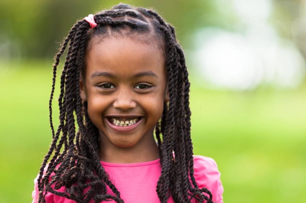 a little girl with braids is smiling for the camera .